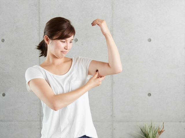二の腕の筋肉・脂肪の付き方を確認する女性