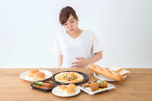 ダイエットの妨げにもなりやすい、脂質や糖質が多く含まれる食事を食べ過ぎてしまっている女性