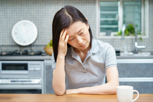 頭を抱えている女性（頭痛、ストレス、悩み、自律神経の乱れなど）