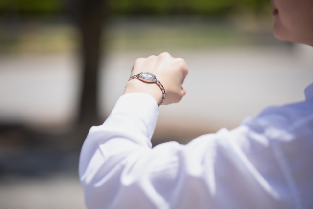 時計を気にしている、時間に追われている女性