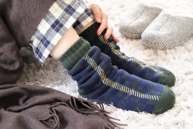 温かい靴下やブランケットで冷え対策をしている女性