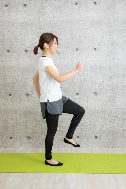 スポーツウエアでもも上げをする女性