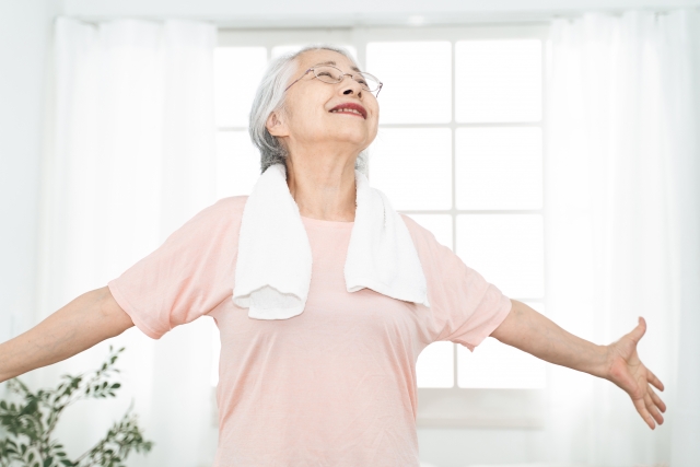 屋内で呼吸を整え、リラックスしているシニア世代の女性（上半身のストレッチ、深呼吸）