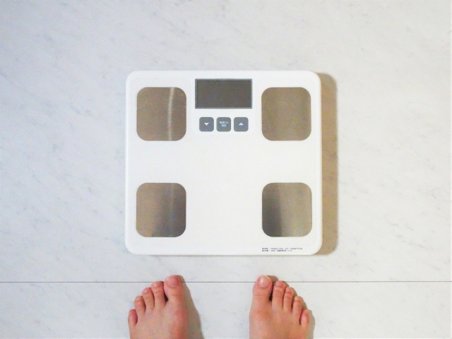 体重計（体組成計）の前に立つ女性