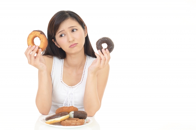 ダイエットの妨げにもなりやすい、カロリー、糖質、脂質の高い菓子パンを持つ女性